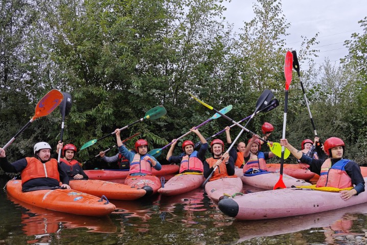 Gruppenfoto - Teilnehmende der Kajaktour in ihren Kajaks auf der Ruhr, eng beieinander heben die Paddel in die Höhe