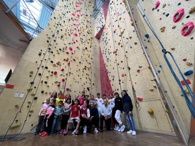 Feriendeutschgruppe vor der hohen Kletterwand in den Wupperwänden